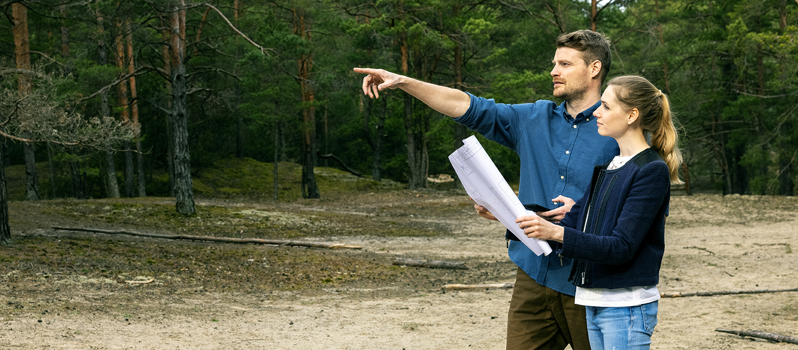 Looking at plans and pointing to land for purchase.