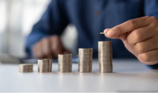 Blurred person in background with hand stacking coins